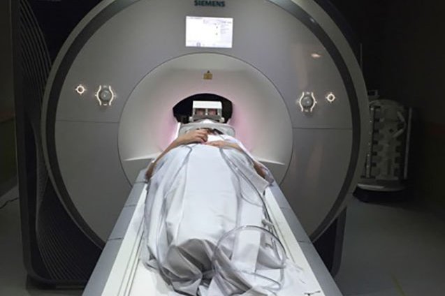 Patients lies on bench as he enters the MRI tunnel for a scan in a hospital.