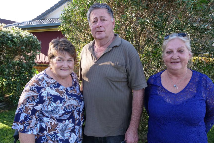 Joan and her husband Garry stand together and support worker Karren beside him in her home front garden 